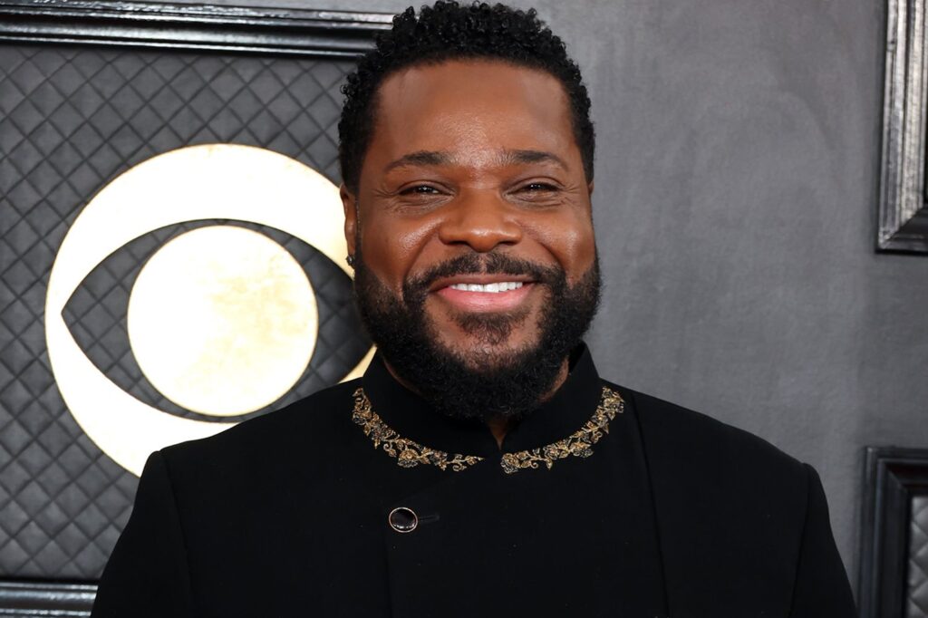 Malcolm-Jamal Warner smiling in a recent promotional photo, remembering the beloved actor and artist